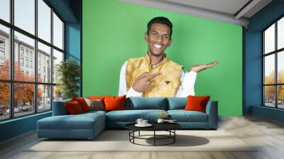 Indian boy smiling with his hands up on the green background Wall mural