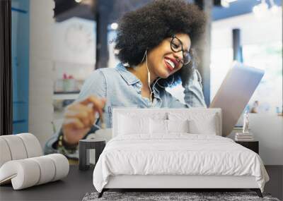 Beautiful afro american woman using mobile and laptop in the coffee shop. Wall mural