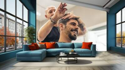 Hairstylist making men's haircut to an attractive man. Wall mural