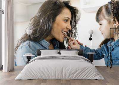 Mother eating chocolate with her daughter. Wall mural