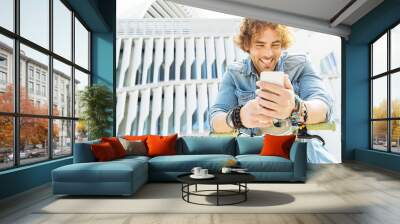 Portrait of Handsome young man smiling when he is using his mobi Wall mural