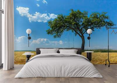 A tree under a blue sky over a crop field Wall mural