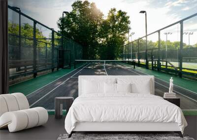 Summertime scene of elevated sport courts with nets in a public park setting. Courts are used for paddle tennis or pickleball play. Floor surface is green and blue with white boundary lines. Wall mural