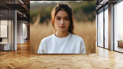 Casual female model in white sweatshirt posing for mockup with serene field backdrop Wall mural