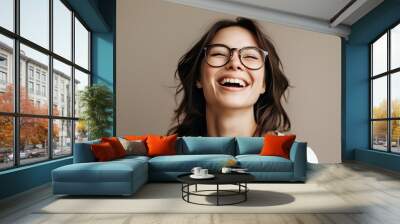 joyful woman in glasses radiating laughter against a soft neutral backdrop Wall mural