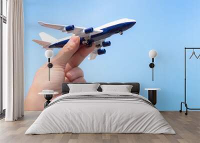 Airplane model in hand on sunny sky. Concepts of travel, transportation Wall mural