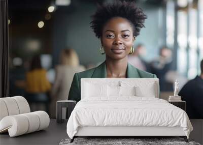 Young African American businesswoman with a short afro, wearing green blazer, standing in a modern co-working space with a blurred background of colleagues. Creative agency manager, startup workplace Wall mural