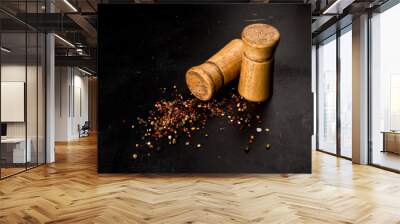 Salt and pepper in wooden salt shakers on a black background Wall mural