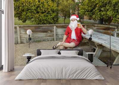 A Santa Claus at Christmas time in  the Australian summer holding a beer Wall mural