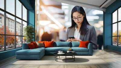 young Asian businesswoman using smartphone in office Wall mural