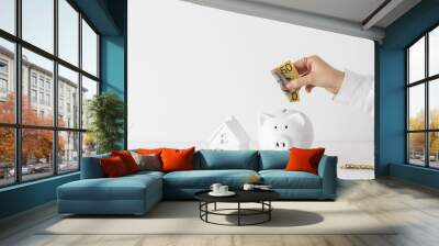 Women placing Australian dollar fifty 50 note into savings white piggy bank money box with copyspace Wall mural