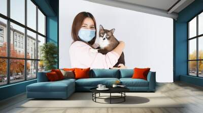 Asian beautiful happy woman wearing a medical protection face mask for protect the coronavirus, filter dust PM 2.5, cold and allergic to cat fur and she carry a cat on the white background Wall mural