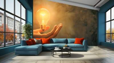 Hand Holding a Lightbulb: A hand holding a glowing lightbulb, symbolizing a bright idea or innovation.
 Wall mural