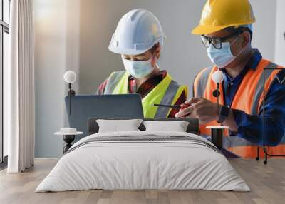 Asian man civil engineer and woman architect wearing blue safety helmet meeting at contruction site. Wall mural