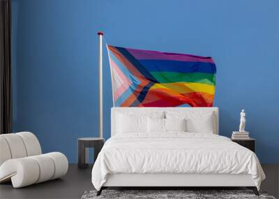 Worldwide LGBTQ community concept with progress pride flag (new design of rainbow flag) waving in the air with blue sky, Celebration of gay pride, The symbol of lesbian, gay, bisexual and transgender. Wall mural