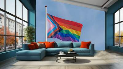 Worldwide LGBTQ community concept with progress pride flag (new design of rainbow flag) waving in the air with blue sky, Celebration of gay pride, The symbol of lesbian, gay, bisexual and transgender. Wall mural