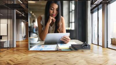 Female businessmen are using the tablet during leisure. She smiles happy. Graphs, documents placed on the table. Wall mural