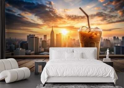 A cold glass of iced coffee on a wooden table next to a cityscape at sunrise, beverage, summer Wall mural