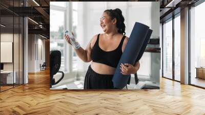 Plus size Asian woman exercises in gym. Beautiful overweight woman in sportswear smiling and happy in fitness. concept of body positive, self-acceptance, weight loss. Wall mural