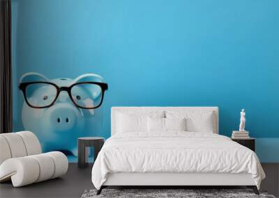 Piggy bank with glasses on blue background Wall mural