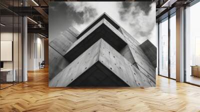 A close-up view of a modern concrete building highlighting angular architectural elements against a dramatic cloudy sky Wall mural