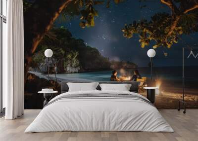 Two friends enjoy a cozy beach bonfire under a starry night sky, surrounded by nature and the sound of waves lapping the shore, on a tranquil beach getaway Wall mural