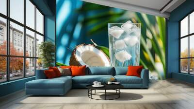 A glass of coconut water with ice cubes, placed beside a cracked open coconut, with palm leaves in the background for a natural, refreshing look. Wall mural