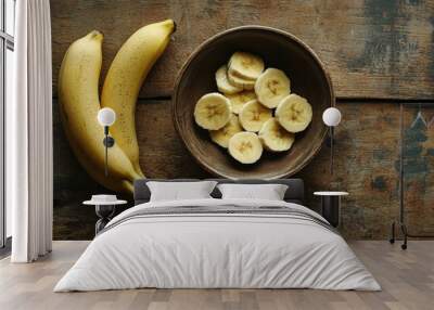 A peeled banana, cut into pieces, arranged in a small bowl on a rustic wooden table. Wall mural