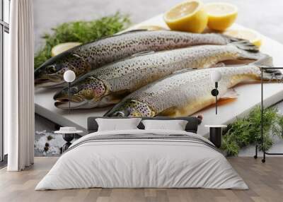 A set of fresh trout displayed on a white cutting board with herbs and lemon slices, ready for cooking. Wall mural