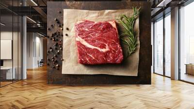 Uncooked ribeye beef, showcasing rich marbling, laid out on a rustic surface with a focus on freshness and quality. Wall mural