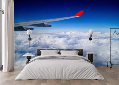 Airplane wing and aerial view during flight with clear blue sky and clouds Wall mural