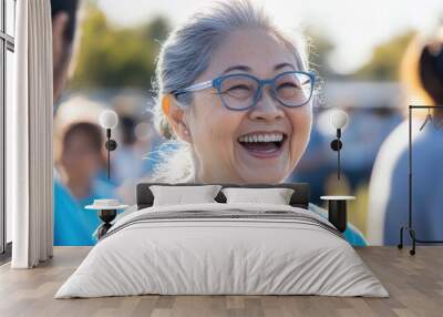 A joyful Asian retiree participates in a community volunteering event, connecting with others and sharing smiles on a sunny day Wall mural