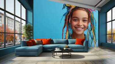 A teenage girl displays her colorful hair and a vibrant hair care product, smiling happily Wall mural