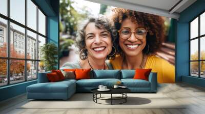 Two women happily smile and pose for a selfie, enjoying a moment of friendship and connection. Wall mural