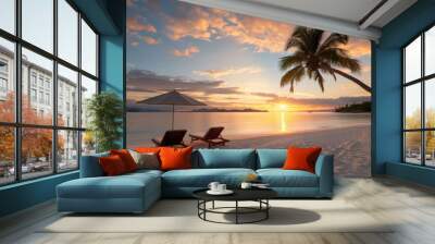 A beach scene with two lounge chairs and an umbrella. The sky is orange and the sun is setting Wall mural