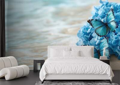 Two blue butterflies are on a beach near the water. The butterflies are surrounded by blue flowers. The scene is serene and peaceful, with the ocean in the background Wall mural