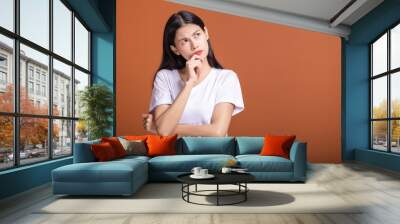 Thinking woman over orange background. Wall mural