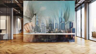 a man using digital tablet, and modern buildings hologram. Real estate business and building technology concept Wall mural