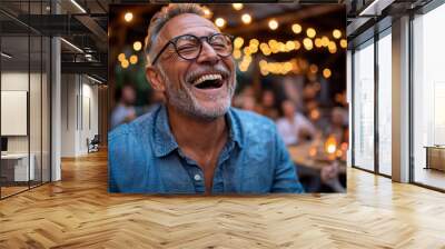 A man laughing joyfully at a family gathering, his face glowing with happiness Wall mural