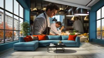 Cook serving food on a plate in the kitchen of a restaurant Wall mural