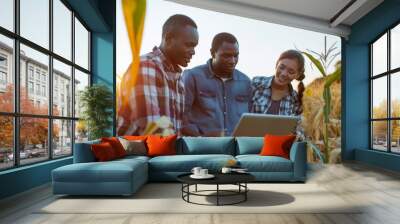 Diversity group of farmers are discussing in the corn field, using a laptop for learning and investment. Two men and one woman. Team work in agribusiness outside.hi five for successful agriculture. Wall mural