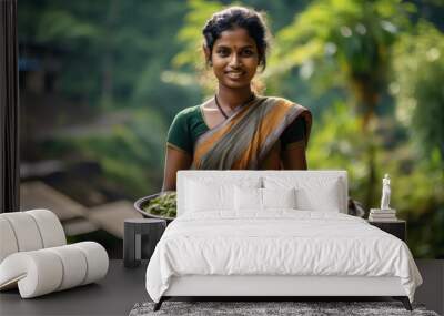 Indian young woman in a sari with a tray of harvested crops, against the backdrop of a village in the jungle. Wall mural