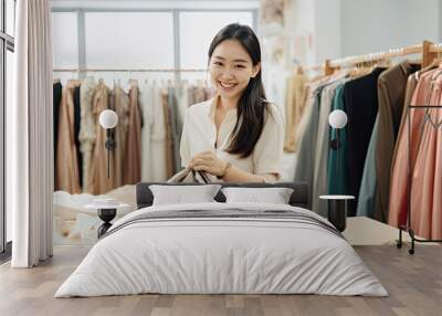 Smiling Asian woman Choose and try on clothe in the Tailor shop. Fashion designer standing in clothing In order to repair, service for customers. Concept Profession Dressmaker designer Wall mural