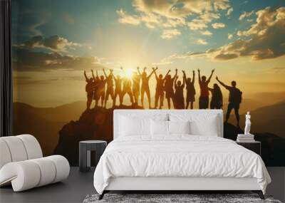 The silhouette of a large group against the setting sun on a mountaintop, their success pose reflecting a shared journey of endurance and triumph. Wall mural