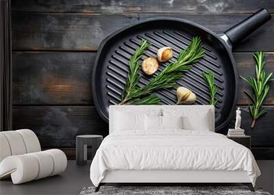 Top view of a sizzling grill pan garnished with garlic and rosemary herbs for cooking Wall mural