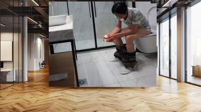 Young asian man holds a roll of toilet paper Going to the bathroom  toilet room Wall mural