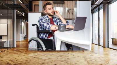 Disabled man with smart phone and laptop Wall mural