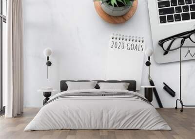 Small blank notebook with 2020 goals text is on top of white marble office desk table with office supplies. New year plan and resolutions concept. Wall mural