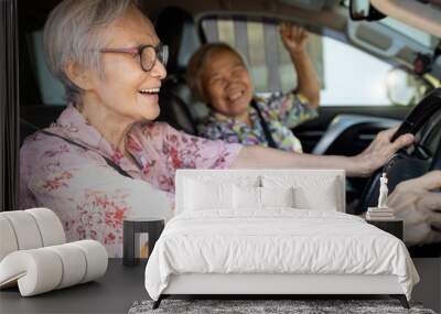 Happy asian senior female driver in her car,enjoy traveling during retirement age with her friend,healthy old people having fun,laughing together,elderly woman driving car,road trip,travel concept Wall mural