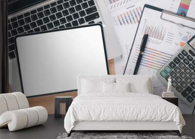 An overhead view of a workspace featuring a laptop, blank tablet screen, financial documents, and a calculator. Wall mural